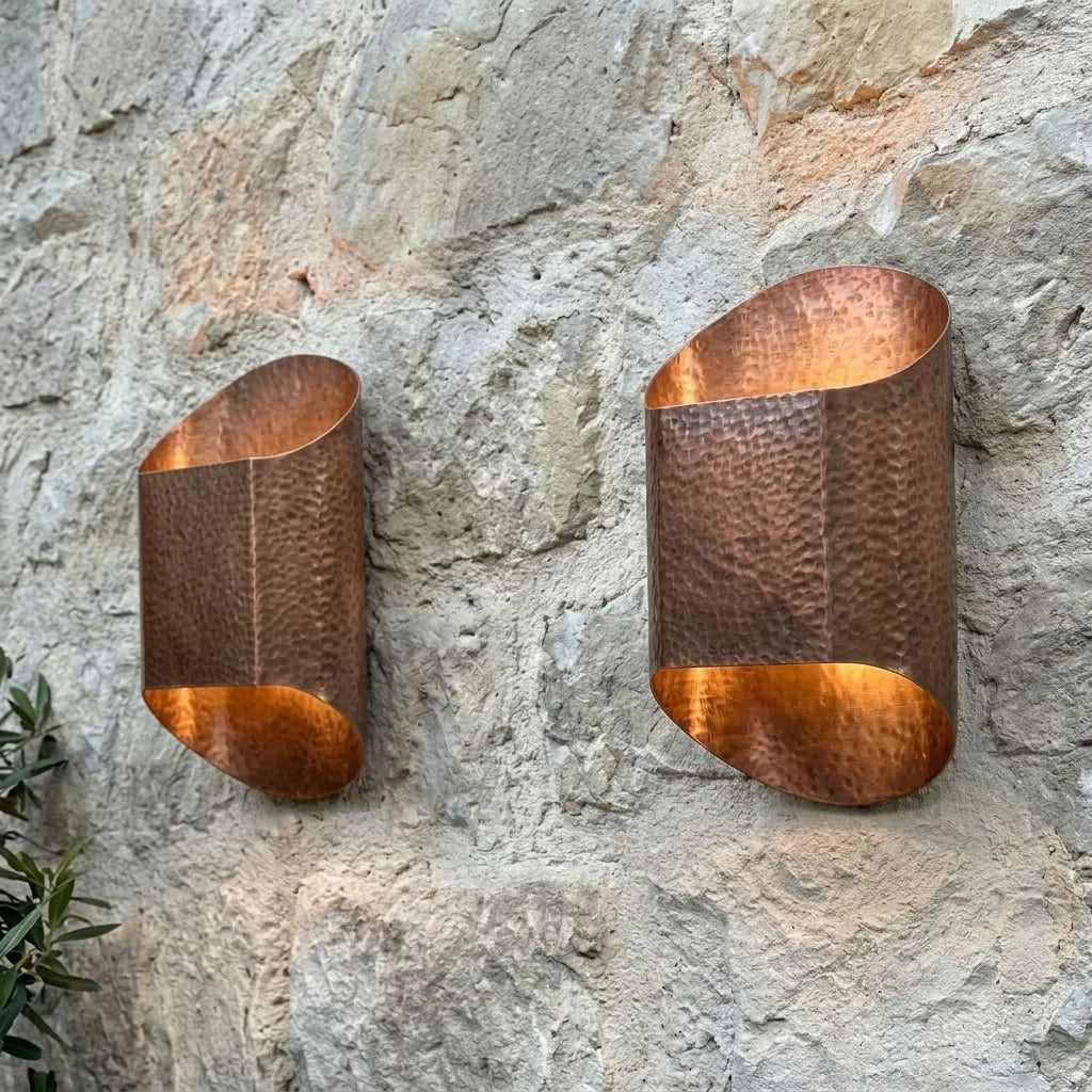 Natural hammered copper sconces on a stone wall