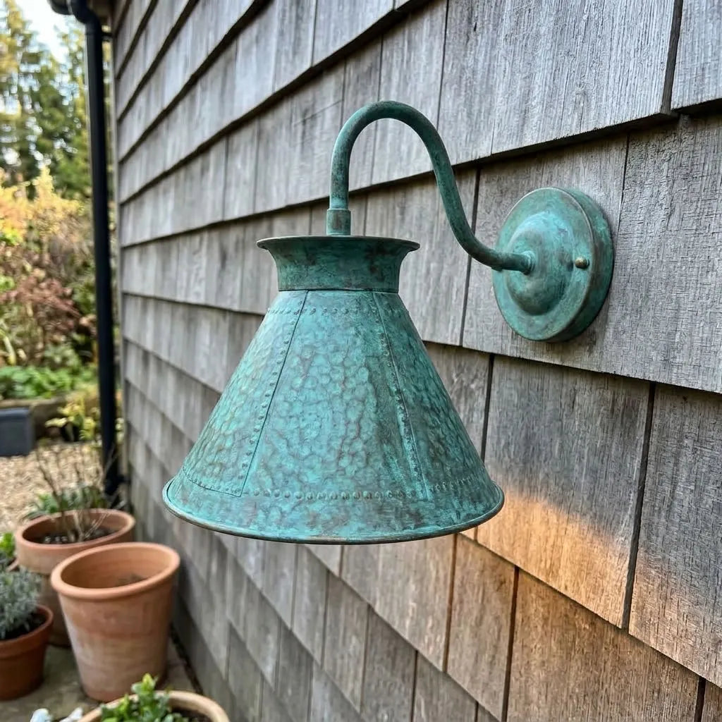 Verdigris gooseneck sconce on a shingled porch wall