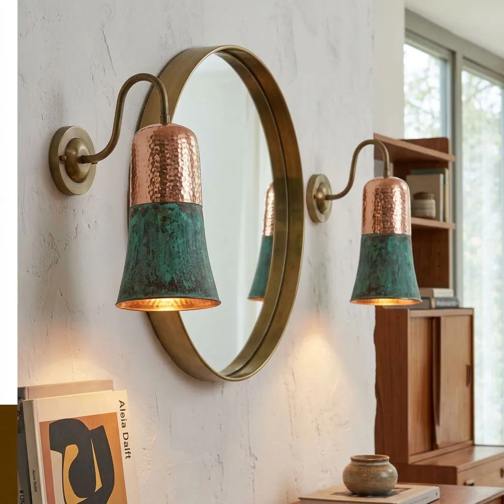 Verdigris copper sconces either side of a round mirror in an entryway