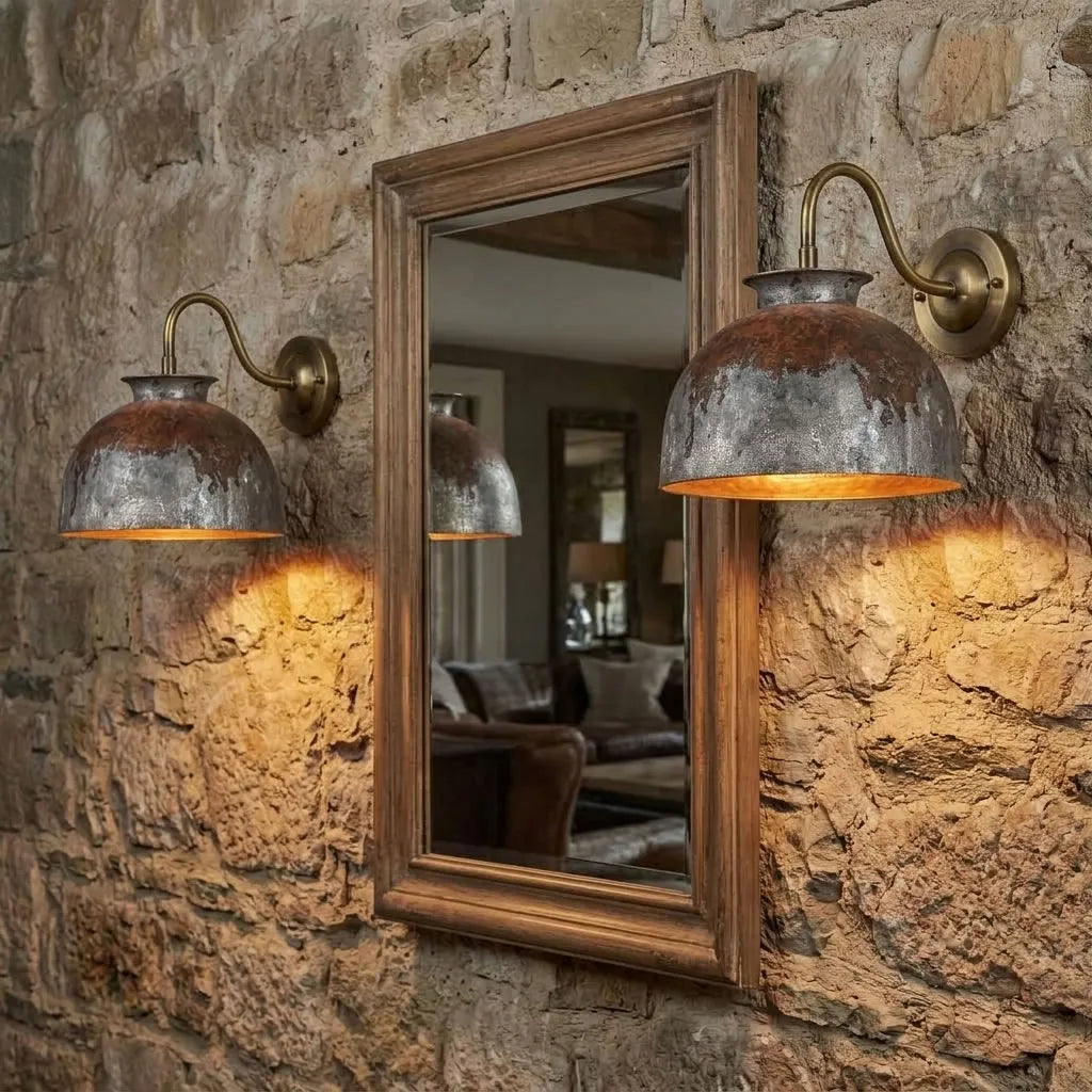 Pair of verdigris copper dome gooseneck sconces flanking a mirror on a stone wall