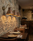 Hammered copper cone shade wall light with brass curved arm