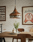 Dining area with wooden table, chairs, and pendant light against a brick wall.