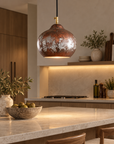 Rustic aged-copper dome pendant light above a modern kitchen island