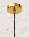 Hammered brass ceiling canopy and black cord detail for sculptural pendant light