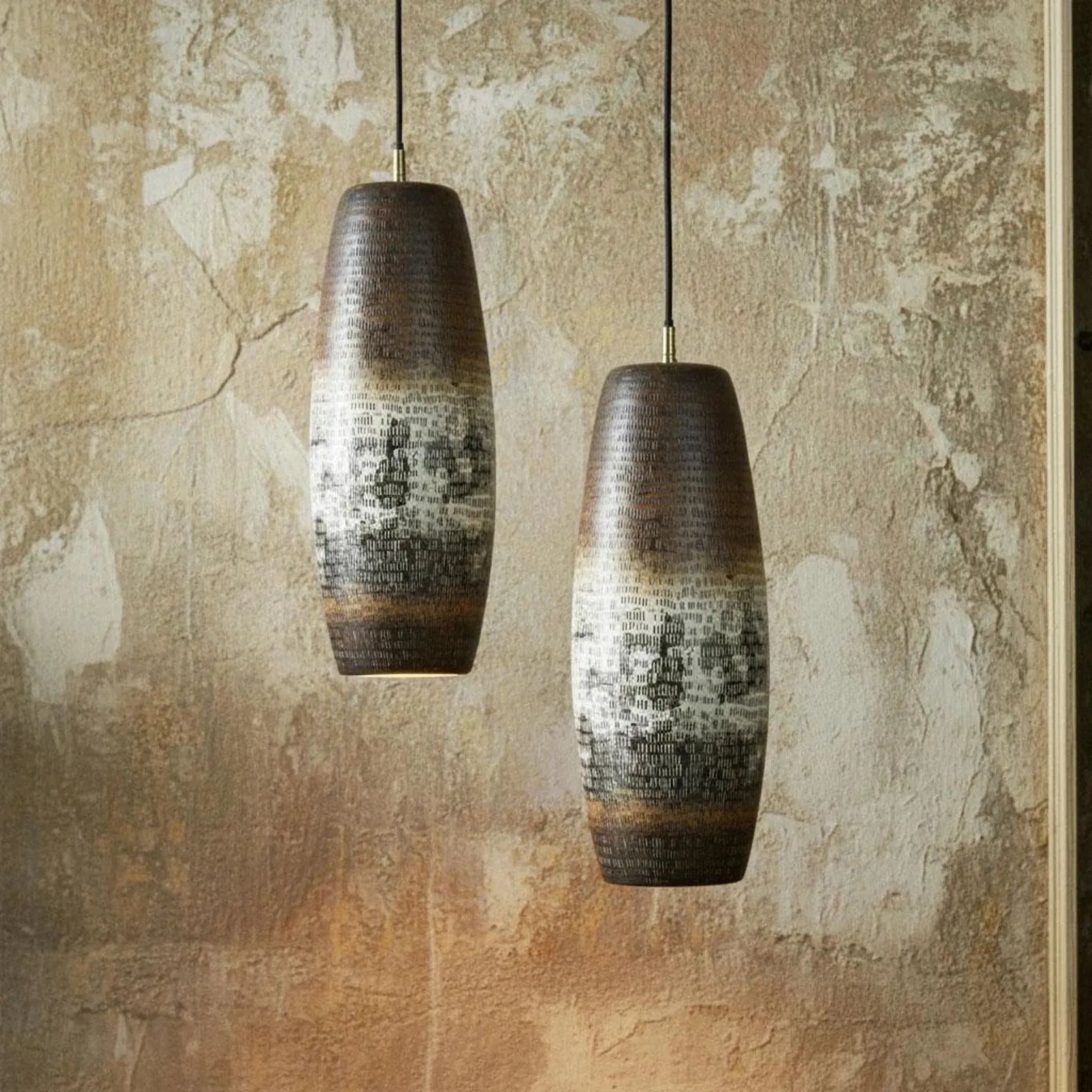 Two ceramic pendant lights hanging against a textured wall.