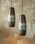 Two ceramic pendant lights hanging against a textured wall.