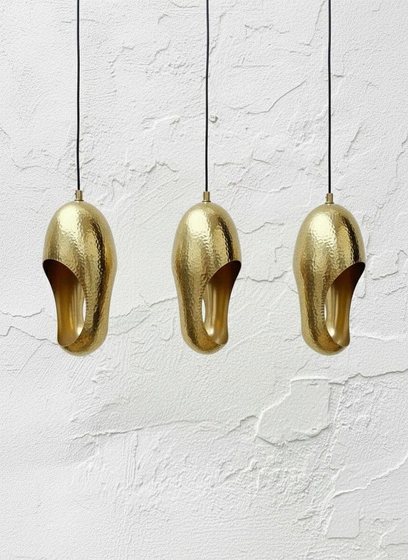 Set of three hammered brass sculptural pendant lights with black cords