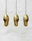 Set of three hammered brass sculptural pendant lights with black cords