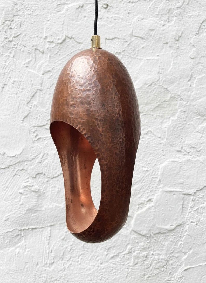 Close-up of one hammered aged-copper sculptural pendant light