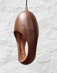 Close-up of one hammered aged-copper sculptural pendant light