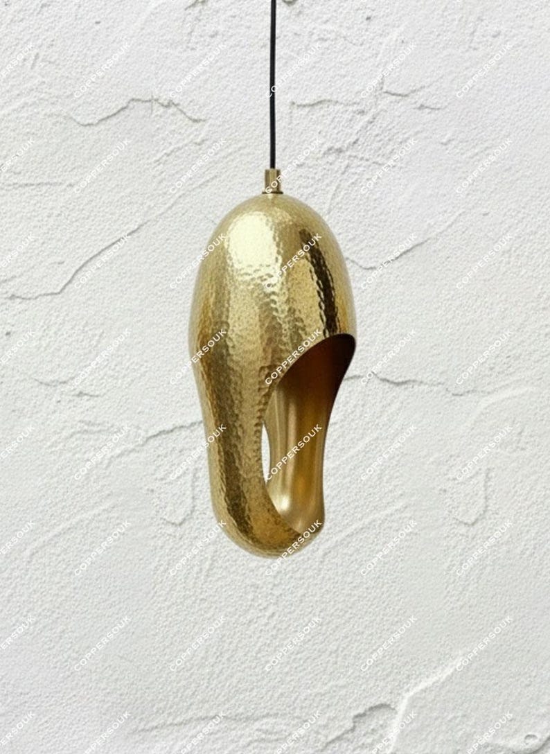 Hammered brass sculptural pendant with a curved opening