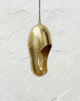 Hammered brass sculptural pendant with a curved opening