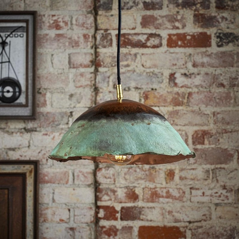 Vintage-style pendant light with a distressed finish hanging against a brick wall.
