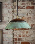 Vintage-style pendant light with a distressed finish hanging against a brick wall.