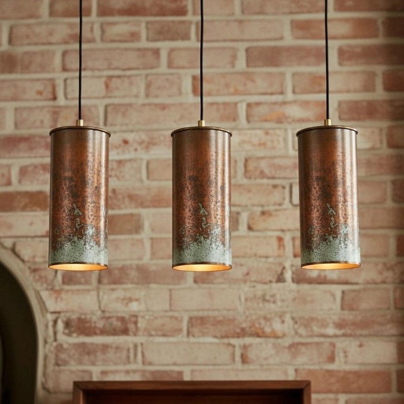 Three cylindrical pendant lights hanging against a brick wall.
