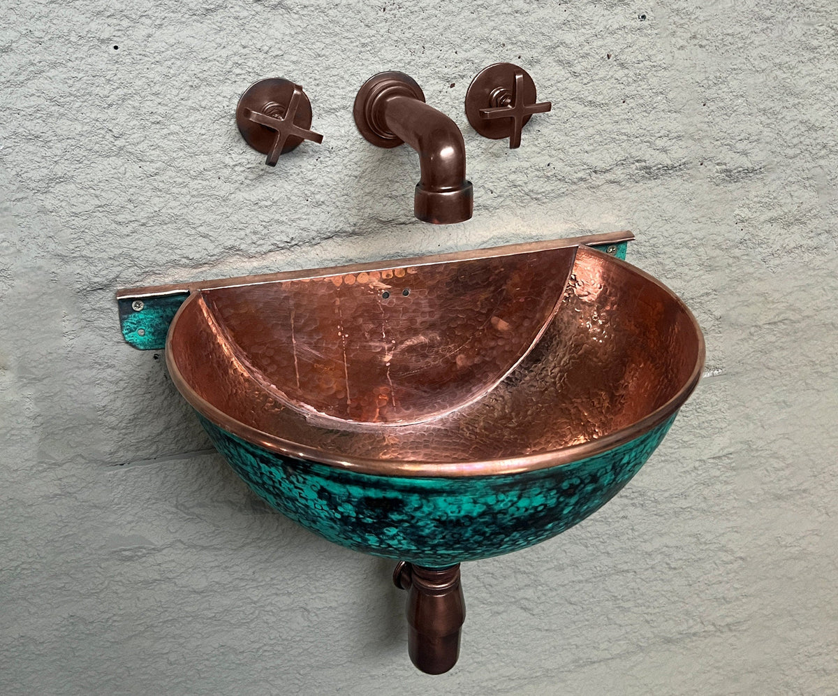 Hammered copper interior and green-patina exterior of wall-mounted bathroom sink