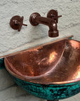 Close-up of wall-mounted hammered copper sink and matching faucet