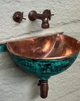 Wall-mounted green-patina copper bathroom sink with faucet and bottle trap