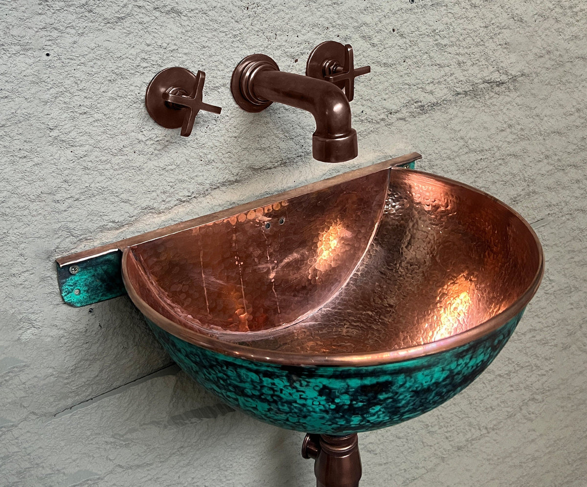 Aged-copper wall faucet above handcrafted green-patina copper sink
