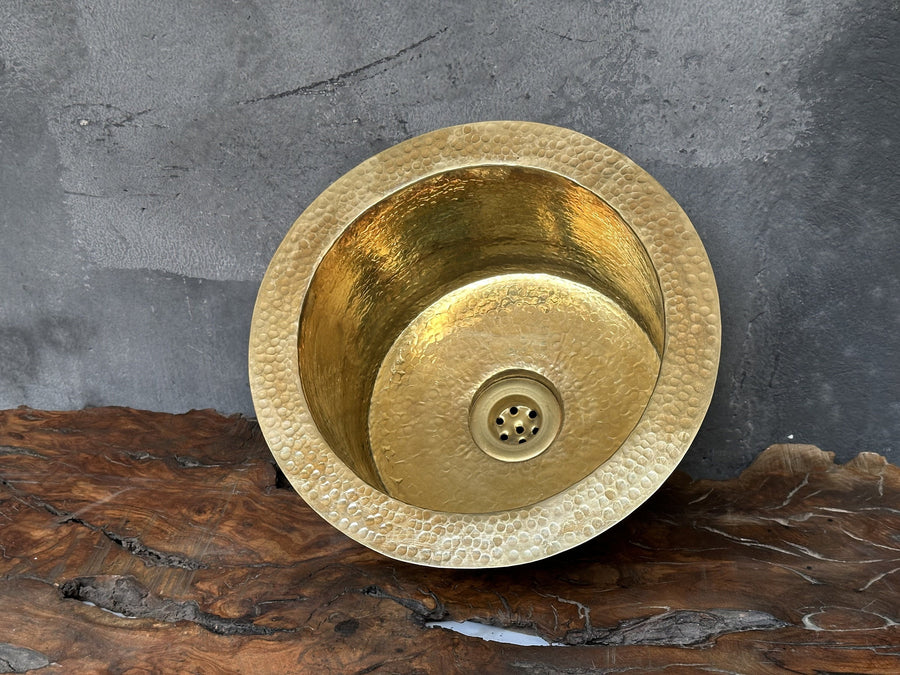 Hammered unlacquered brass round bar sink with a brass drain