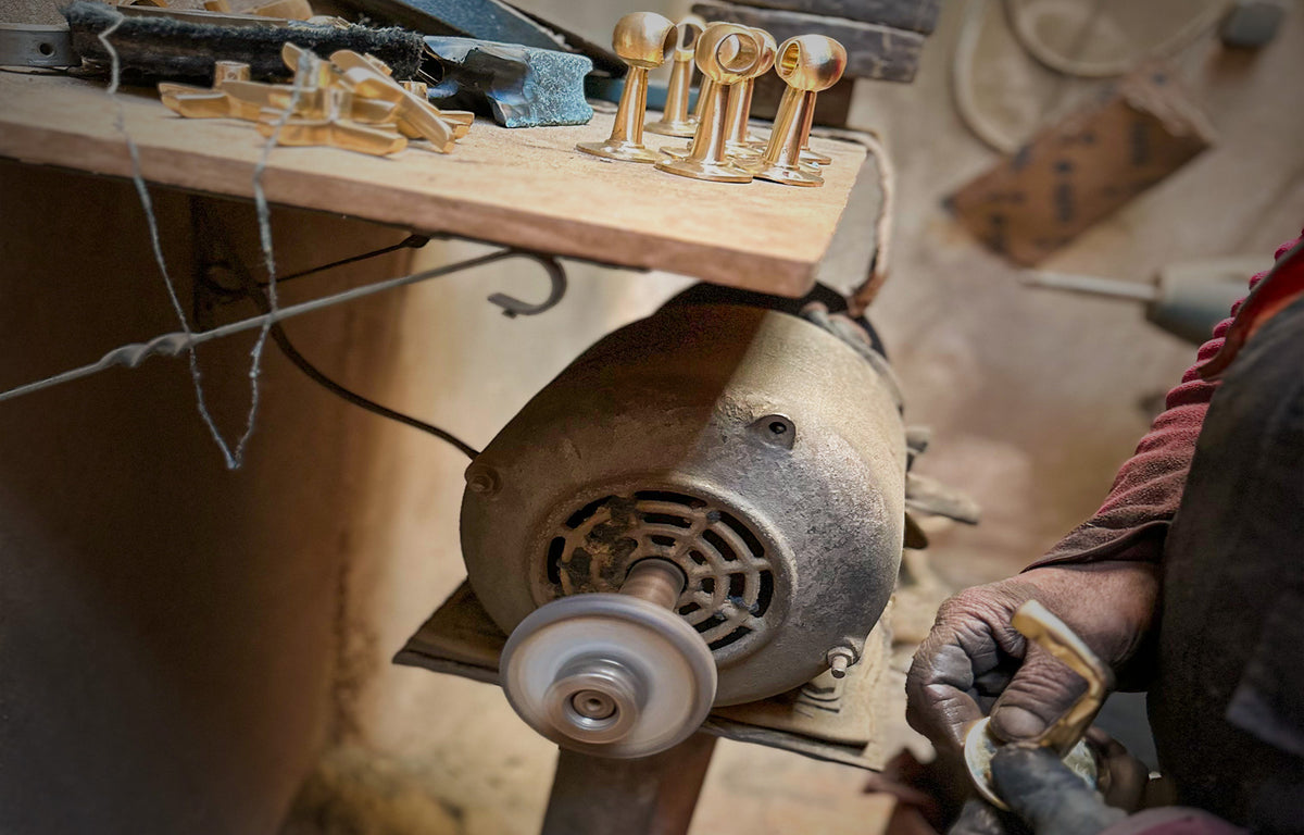 Artisan polishing solid brass fittings on a workshop buffing wheel